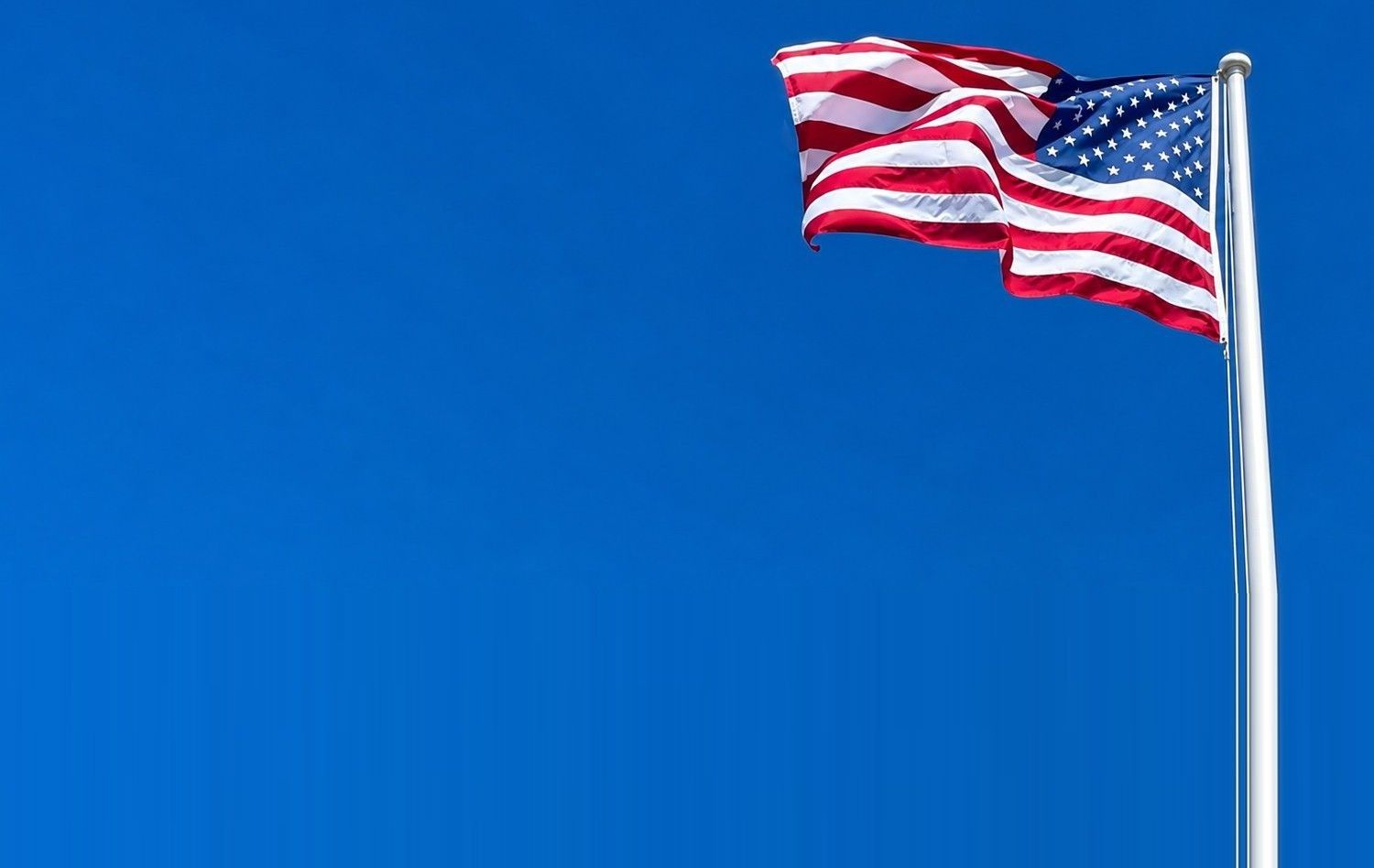 American flag waving against a clear blue sky