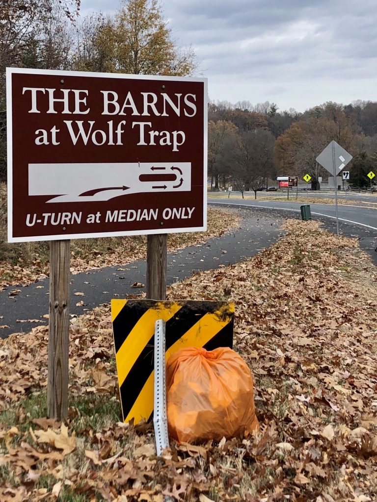 Trash bag underneath a road sign next to a road